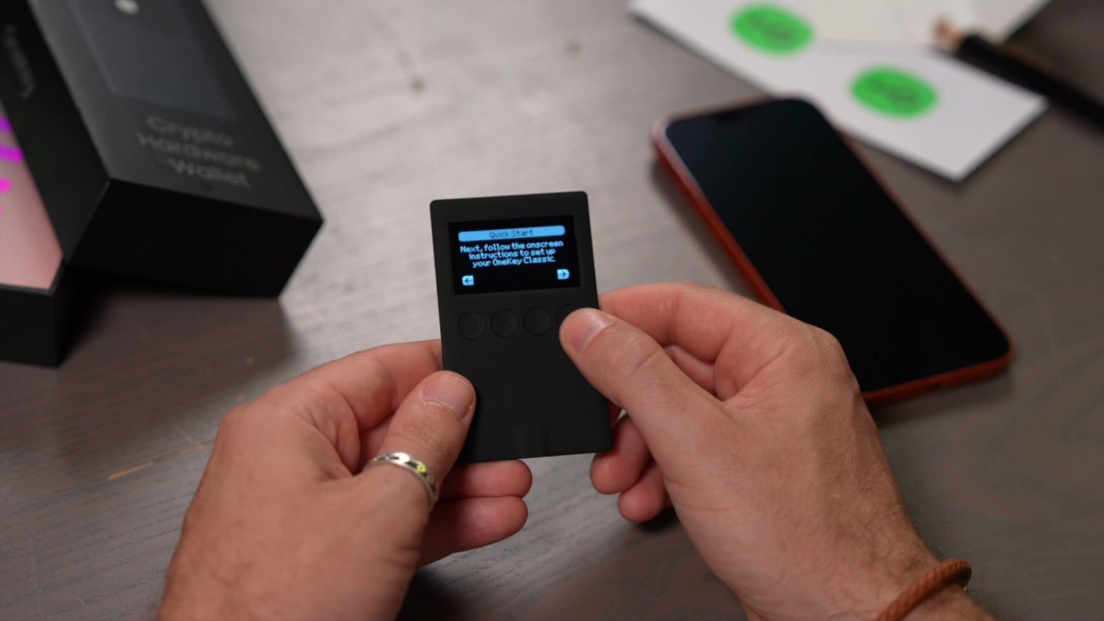Hands holding OneKey hardware wallet with display active